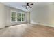 Bright bedroom featuring hardwood floors, a ceiling fan, and a large window offering wooded views at 3915 Ashley Trace Sw Ct, Lilburn, GA 30047
