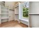 Walk-in closet with custom white shelving, storage, bench, and natural light at 3915 Ashley Trace Sw Ct, Lilburn, GA 30047