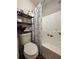 A bathroom featuring a toilet with black shelving, a combined shower and tub with white anchor shower curtain at 4284 Village Green W Cir, Conyers, GA 30013