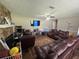 Comfortable living room featuring a stone fireplace, ceiling fan, and plush leather seating at 4284 Village Green W Cir, Conyers, GA 30013