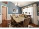 Dining room featuring hardwood floors, wainscoting, modern chandelier, and a large window for natural light at 5742 Riverside Walk Dr, Sugar Hill, GA 30518