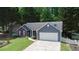 Charming blue home with red shutters, green lawn, and a two-car garage nestled among lush green trees at 5742 Riverside Walk Dr, Sugar Hill, GA 30518