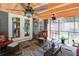 Cozy screened patio with wood ceiling, stone flooring, ceiling fans, and comfortable seating area at 5742 Riverside Walk Dr, Sugar Hill, GA 30518