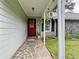 Inviting front porch with stone tiling, a red front door, and hanging potted plants at 11072 Shannon Cir, Hampton, GA 30228