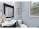 Powder room featuring a white vanity, decorative mirror, and soft blue walls at 1614 Rucker Rd, Alpharetta, GA 30009