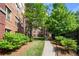 A lush walkway leads past mature trees to a building with brick facade and well-maintained landscaping at 200 River Vista Dr # 120, Atlanta, GA 30339