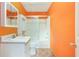 Bright bathroom with orange walls, white cabinets, and a shower-tub combo with sliding glass doors at 259 Pine Valley Dr, Powder Springs, GA 30127