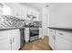 Modern kitchen features stainless steel appliances, white cabinets, and a mosaic backsplash at 4638 Arrow Wind Dr, Powder Springs, GA 30127