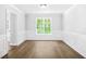 Bright, empty living room with wainscotting, featuring hardwood floors and a large window at 4638 Arrow Wind Dr, Powder Springs, GA 30127