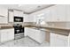 Well-lit kitchen features white cabinets, stainless steel appliances, and marble tile flooring at 771 Franklin Mill Trce, Loganville, GA 30052