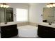 Bathroom featuring double sinks, bathtub with neutral tile and mirrors at 4020 Alligator Pt, Cumming, GA 30028