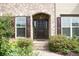 Elegant front entrance showcasing brick detail, lush landscaping, and a classic paneled door at 4020 Alligator Pt, Cumming, GA 30028