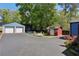 View of the backyard with a two-car garage, fire pit, storage building, and a large parking pad at 727 Channing Nw Dr, Atlanta, GA 30318