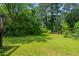 Lush green backyard with mature trees and privacy, partially enclosed by a chain-link fence at 29 Parkwood Ne Dr, Kennesaw, GA 30144