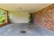 Large covered patio with a brick wall, cement floor, and open doorway to the backyard at 29 Parkwood Ne Dr, Kennesaw, GA 30144