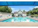 Community pool with multiple lounge chairs and view of the clubhouse on a sunny day at 642 Towering Pine Trl, Lawrenceville, GA 30045