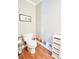 Powder room with hard wood floors, base board artwork, and a white toilet and shelving at 811 Ivy Ridge Dr, Loganville, GA 30052
