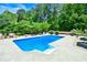 Beautiful backyard swimming pool with a bright blue liner and concrete patio with lush landscaping at 811 Ivy Ridge Dr, Loganville, GA 30052