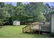 Expansive backyard with a wooden deck, lush lawn, and a storage shed surrounded by mature trees at 173 Elder Dr, Social Circle, GA 30025