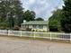 Charming single-story home with a green roof and a white picket fence bordering a manicured front yard at 173 Elder Dr, Social Circle, GA 30025