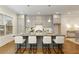 A kitchen showcases a gray island with marble countertop, seating, stylish light fixtures, and modern cabinetry at 323 Concord St, Alpharetta, GA 30009
