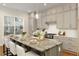 A kitchen showcases a gray island with marble countertop, seating, stylish light fixtures, and modern cabinetry at 323 Concord St, Alpharetta, GA 30009