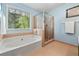 Bright bathroom features a soaking tub beneath a window and a separate glass enclosed shower at 5245 Olde Mill Rd, Woodstock, GA 30188