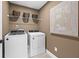 A well-lit laundry room with a washer, dryer, storage shelf, and decorative wall art at 707 Mirror Lake Parkway Way, Villa Rica, GA 30180