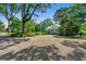 Gravel driveway to a charming blue home, surrounded by mature trees and lush greenery on a sunny day at 7550 Fielder Rd, Jonesboro, GA 30236