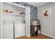 Convenient laundry room includes a washer, dryer, shelving, and stylish wallpaper at 10312 Waterford Ne Rd, Covington, GA 30014
