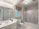 Bathroom featuring a shower-tub combo with sliding glass doors, a large mirror and a window view at 3580 Treeline Ne Pass, Roswell, GA 30075