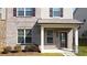 Inviting townhome entrance featuring a covered porch, manicured shrubs, and brick facade at 2692 Pearl Ridge Trce, Buford, GA 30519