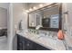 Bathroom featuring a double sink vanity with marble countertop, framed mirror, and elegant lighting at 1610 Turtle Pond Dr, Hoschton, GA 30548