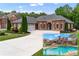 Beautiful brick home featuring a well-manicured lawn, a large driveway, and an in-ground pool with a waterfall feature at 1610 Turtle Pond Dr, Hoschton, GA 30548