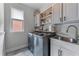 Modern laundry room with washer, dryer, utility sink, and shelving at 1610 Turtle Pond Dr, Hoschton, GA 30548