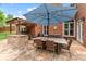 Brick outdoor kitchen with stone countertop, grill, and dining table shaded by a large umbrella at 1610 Turtle Pond Dr, Hoschton, GA 30548