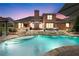 Inviting in-ground pool with a waterfall feature and an outdoor seating area at dusk at 1610 Turtle Pond Dr, Hoschton, GA 30548