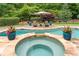 Beautiful in-ground pool with a spa, lounge chairs, umbrella and landscaped surroundings at 1610 Turtle Pond Dr, Hoschton, GA 30548