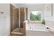 Primary bathroom featuring glass-enclosed shower, bathtub, and neutral tile at 1955 Piedmont Cove Ln, Cumming, GA 30040