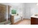 Primary bathroom featuring glass-enclosed shower, bathtub, and ample natural light at 1955 Piedmont Cove Ln, Cumming, GA 30040