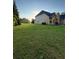 Expansive backyard with lush green grass, mature trees, and a view of the home's exterior at 3 Tiffany Trce, Palmetto, GA 30268