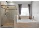 Bright bathroom featuring a glass enclosed shower, separate tub, and window with privacy blinds at 3179 Falls Crest Ct, Buford, GA 30519