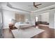 Large main bedroom with tray ceilings, hardwood floors, a fan, and decorative headboard at 3179 Falls Crest Ct, Buford, GA 30519
