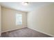 Neutral bedroom with brown carpet, window, and ceiling light fixture at 3242 College St, Atlanta, GA 30337