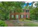 Traditional two-story brick home featuring a lush front yard with mature trees and black shutters at 1201 Justin Ln, Lithonia, GA 30058