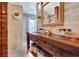 This rustic bathroom features a wood vanity, copper sinks, brick accents, and view into the yard at 150 Gill Ln, Stockbridge, GA 30281