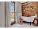 This bathroom features a stand alone tub, wood accents, brick accents, and a view of the yard at 150 Gill Ln, Stockbridge, GA 30281