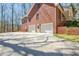 Side view of a brick home showcasing a two-car garage with a large parking area at 150 Gill Ln, Stockbridge, GA 30281