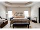 Elegant main bedroom featuring tray ceiling, seating area, and large bed with decorative pillows at 64 Citadel Dr, Hampton, GA 30228