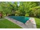 Large in-ground pool with a safety cover, surrounded by lush landscaping and mature trees at 4616 Greensprings Rd, Atlanta, GA 30337